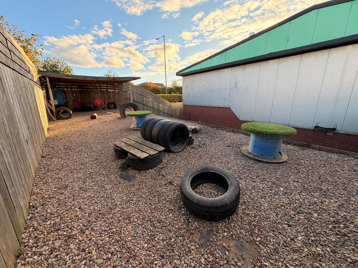 The outdoor paddock with tyres, a bench and a play table on gravel